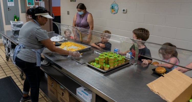 Niños recibiendo comida en la cola de una cafetería