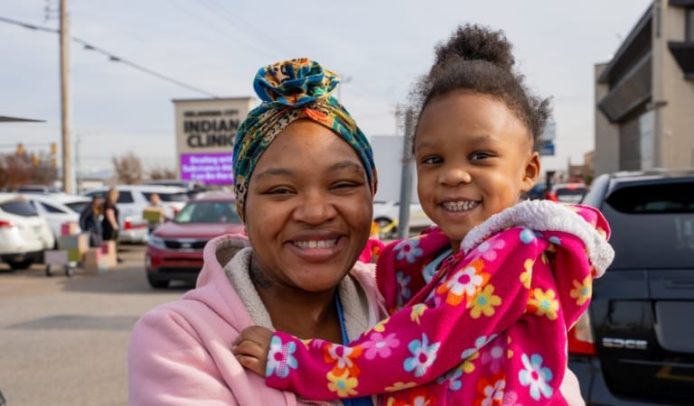 Una madre y su hija sonríen en un evento al aire libre