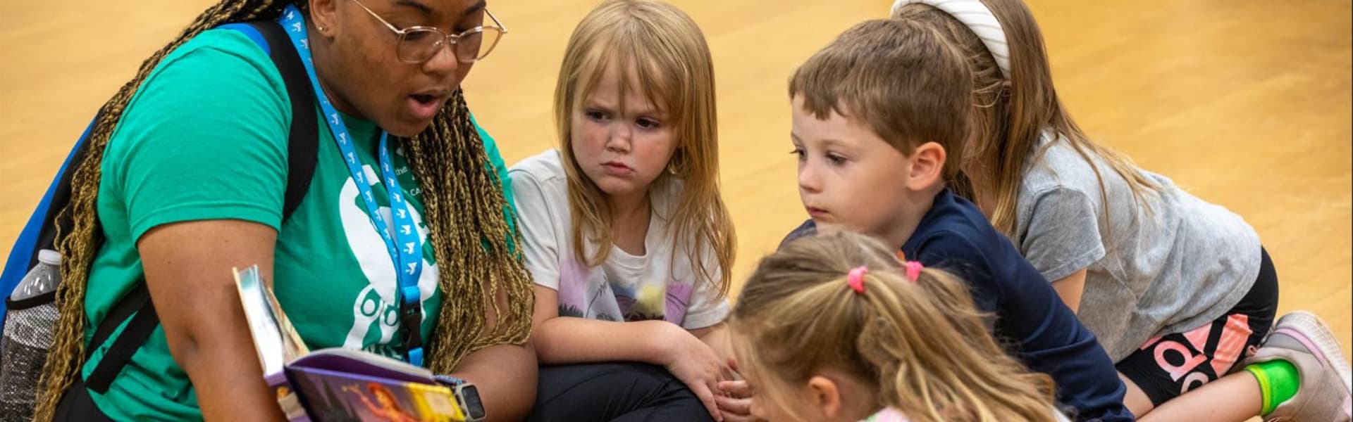 Un profesor y unos niños leyendo un libro en un gimnasio