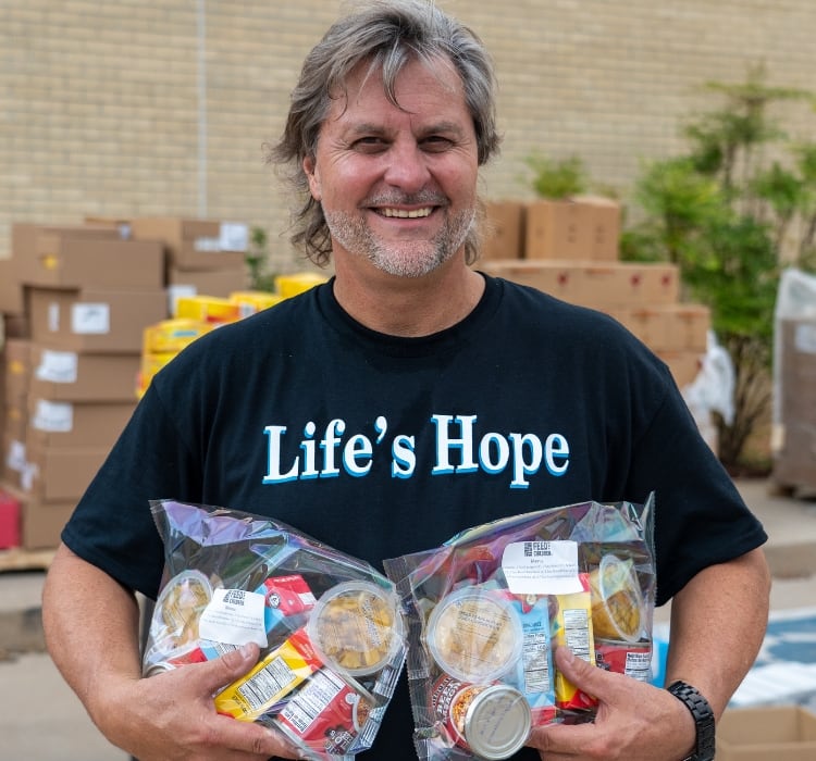 Un voluntario de Life's Hope sostiene alimentos en bolsas