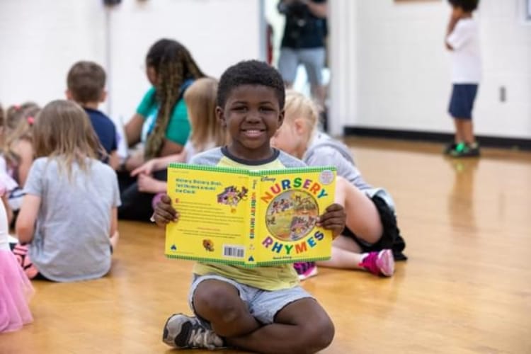 Un niño leyendo un libro en el gimnasio de un colegio