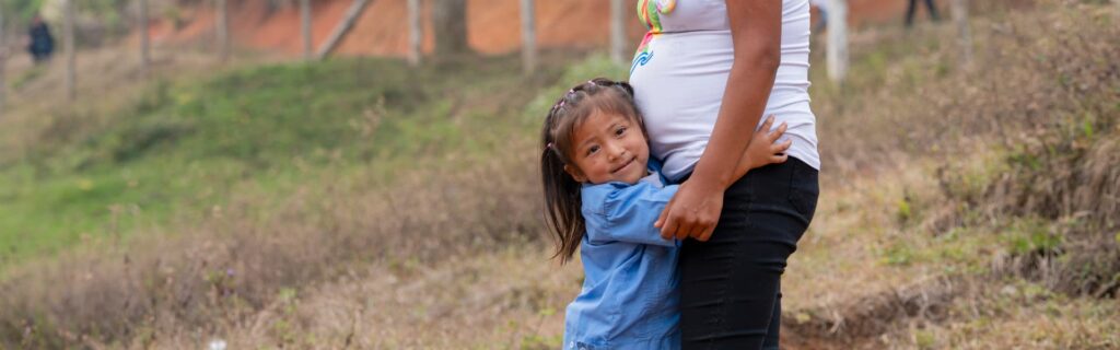 Una niña abraza a su madre embarazada
