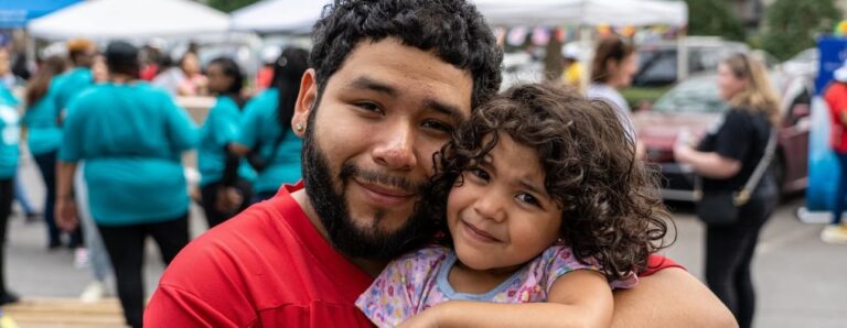 A man and his daughter hugging outdoors at an event