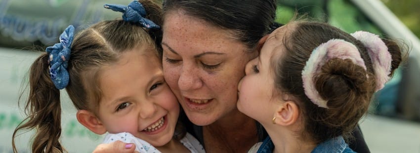 Una madre y sus dos hijos se abrazan al aire libre