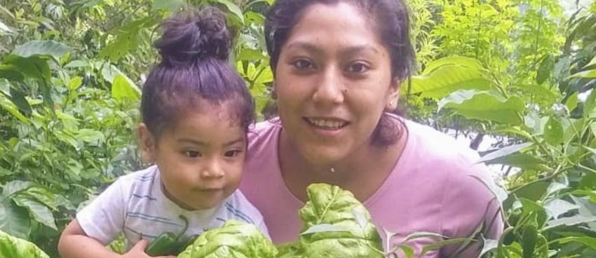 Una madre y su hija al aire libre rodeadas de plantas