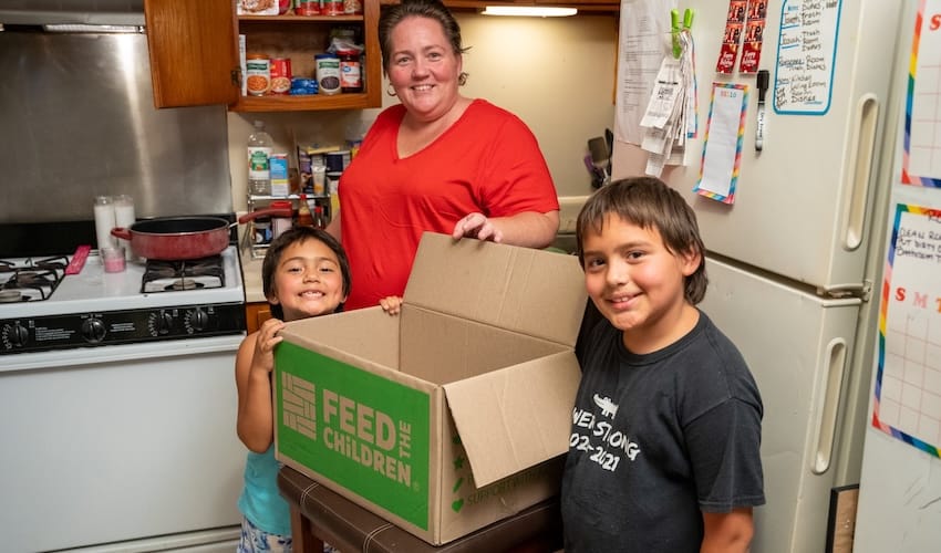 Una mujer y dos niños con una caja en la cocina