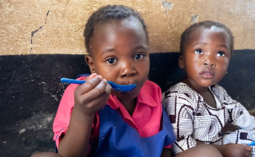Dos niños sentados comiendo en África