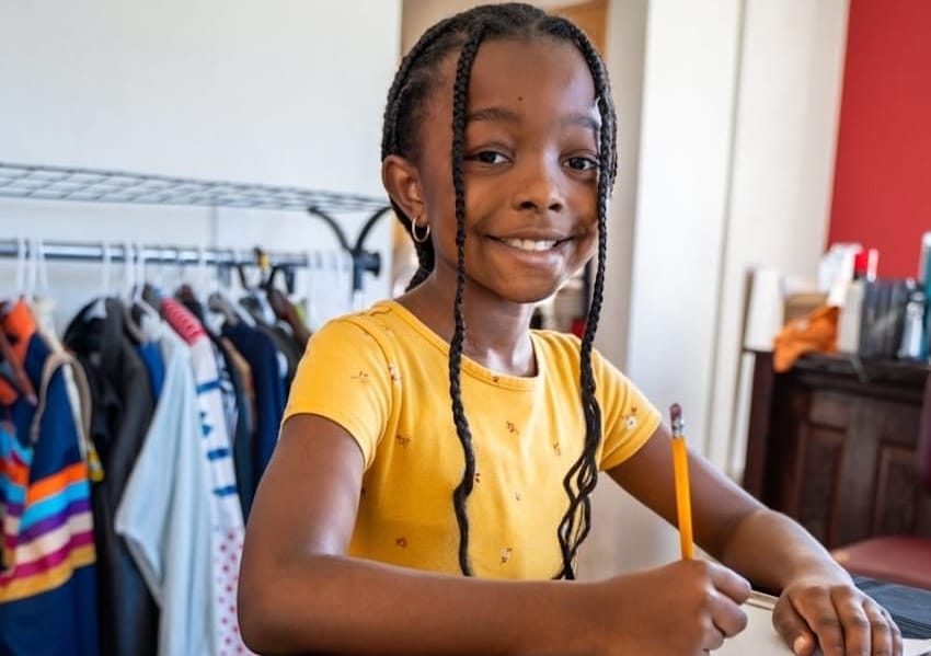 Una niña escribe en un cuaderno en el interior de una casa