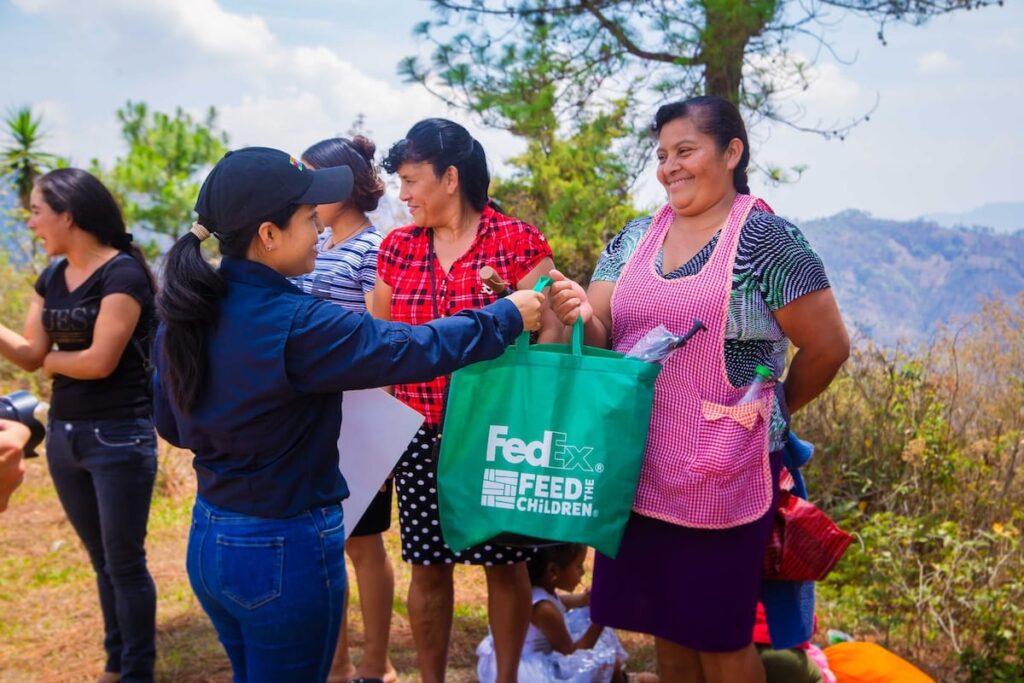 Una mujer reparte bolsas a particulares en un entorno al aire libre