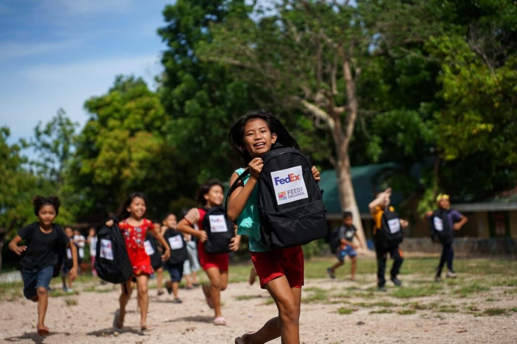 Un grupo de niños corriendo con mochilas de Feed the Children