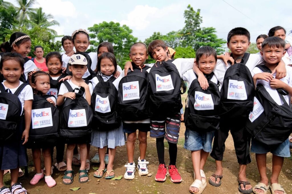 Un grupo de niños con mochilas de Feed the Children al aire libre