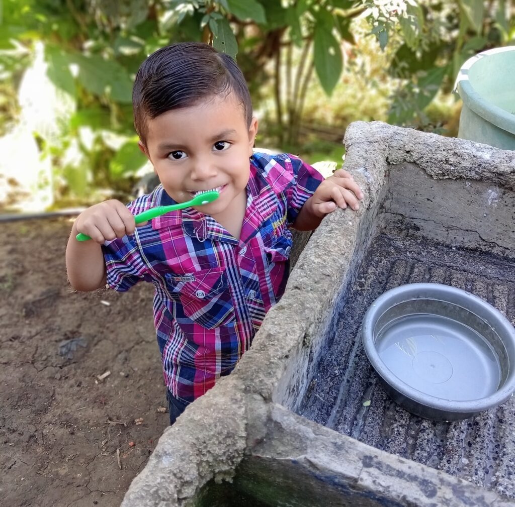 A boy brushing his teeth outdoors.