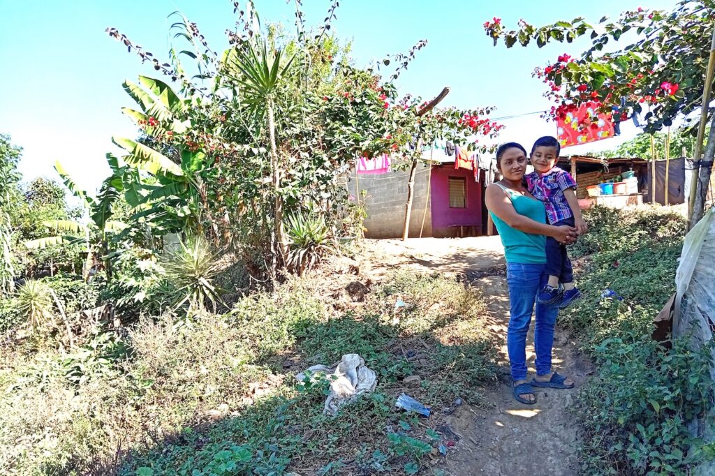 Una madre y un niño en un camino cerca de una casa.