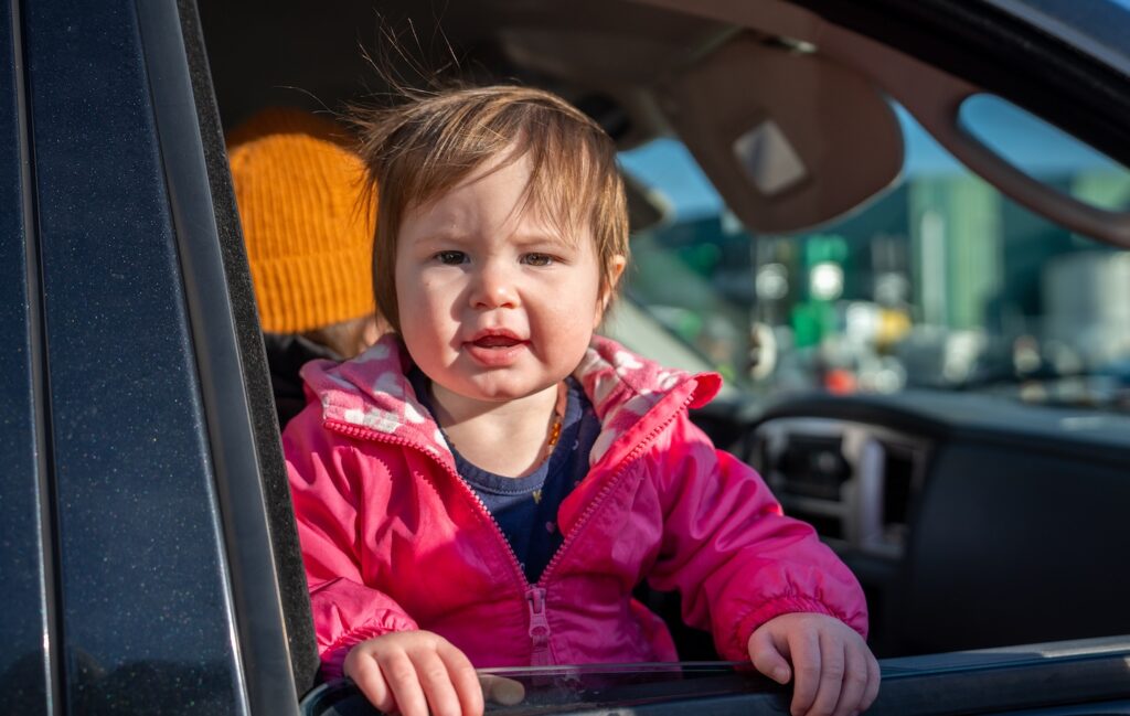 Un niño pequeño mirando por la ventanilla de un coche.