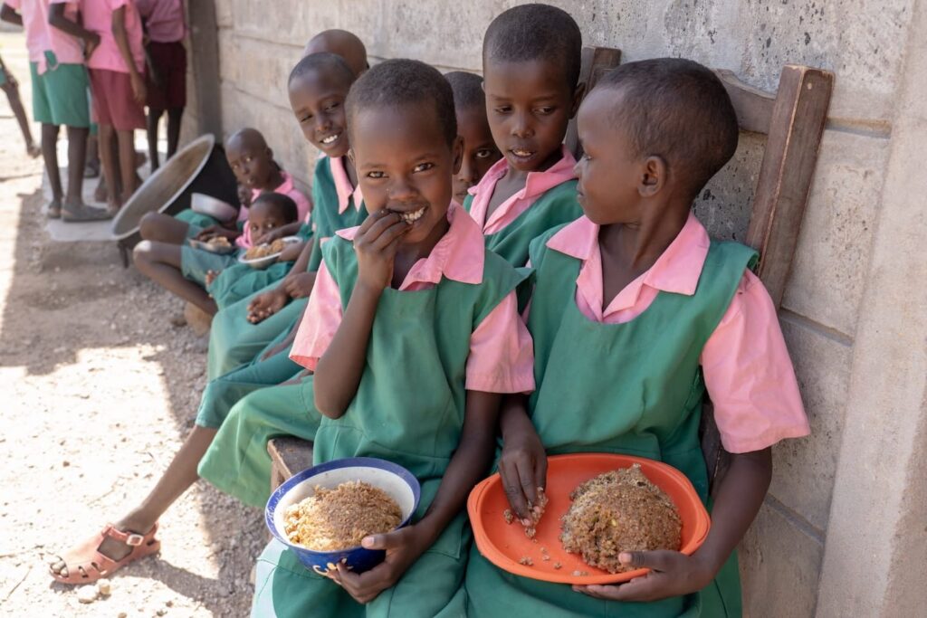 Niños comiendo al aire libre en Kenia.