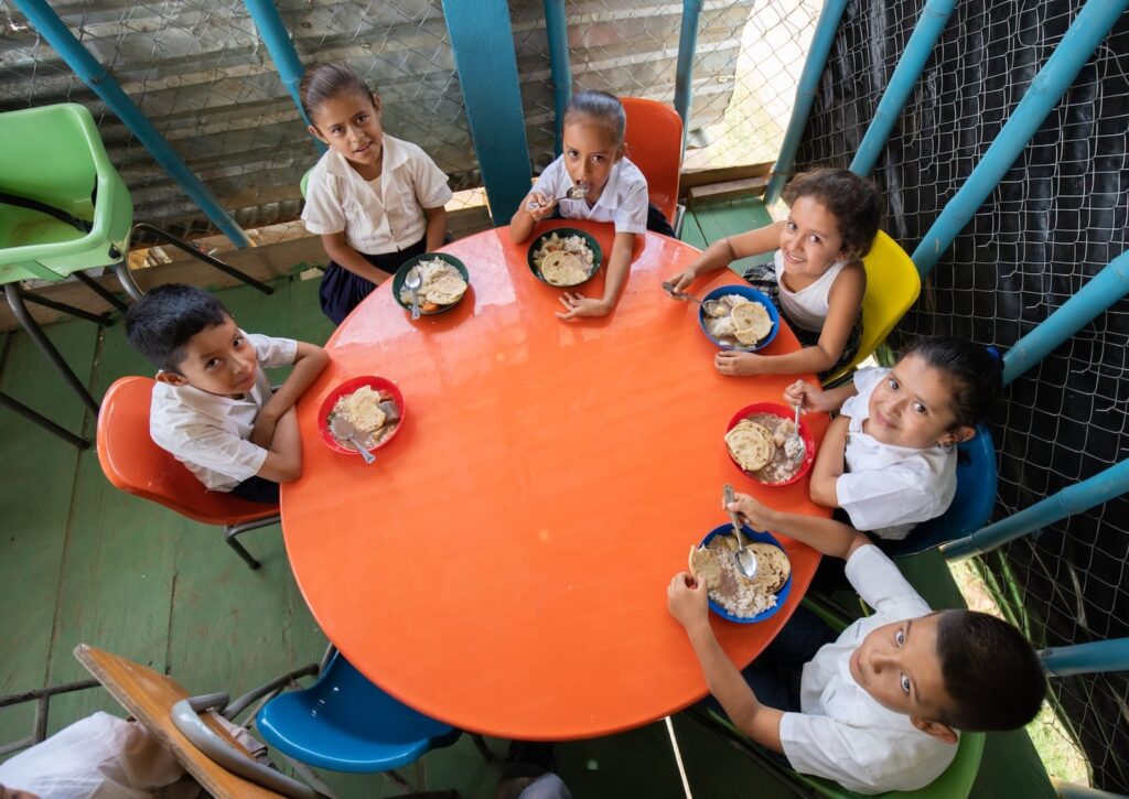 Un grupo de niños comiendo en una mesa circular en Sudamérica.