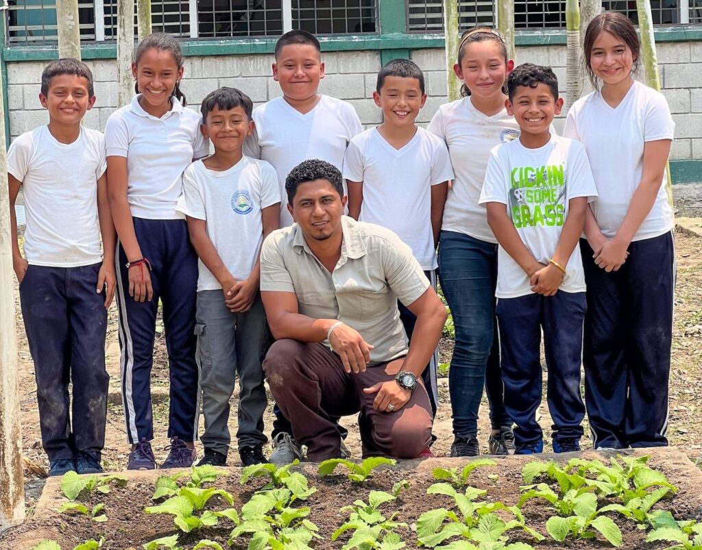 Un grupo de estudiantes de pie frente a un jardín.