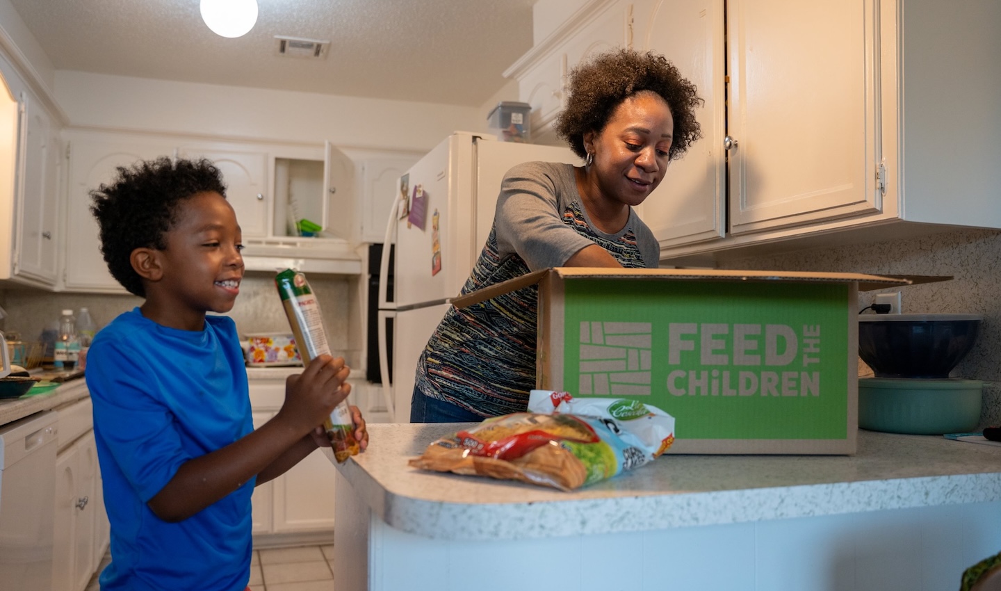 Rose y su hijo con una caja de provisiones en una cocina.