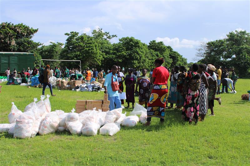Un grupo de trabajadores humanitarios en un campo con bolsas y cajas de suministros.