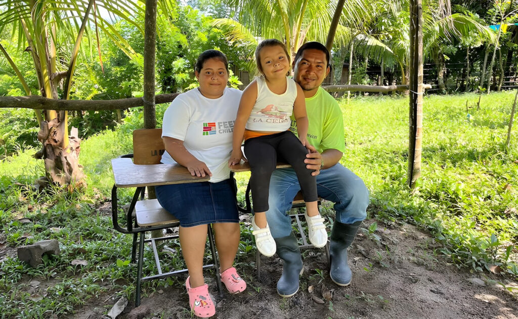 Yensy en un banco con otras personas al aire libre.