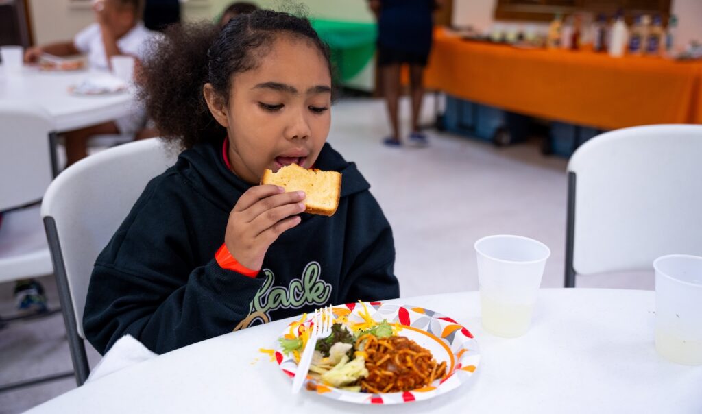 Una niña comiendo un sándwich en el comedor de la escuela.