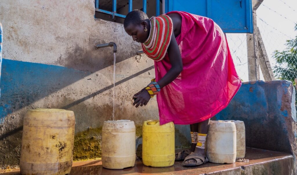 A woman in Kenya collecting water in containers.