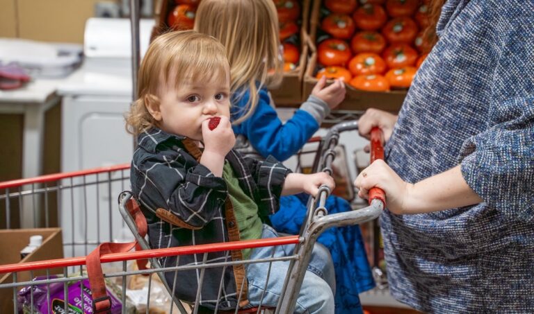 Niños montados en un carrito de supermercado.