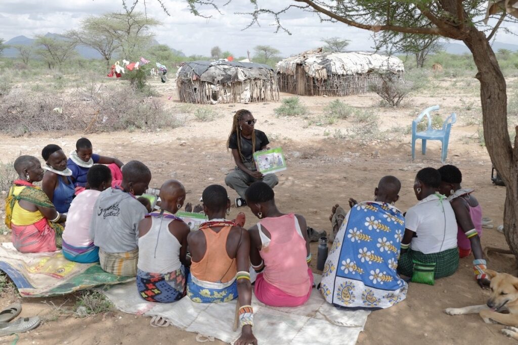 Women assembled on the ground for a care group session in Kenya.